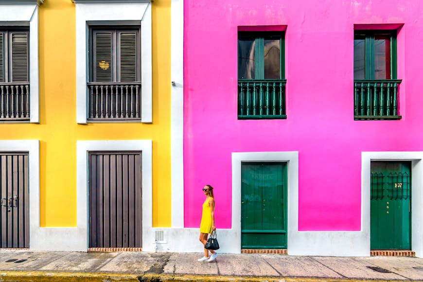 Kvinna i en gul klänning framför färgglada fasader i gamla San Juan
