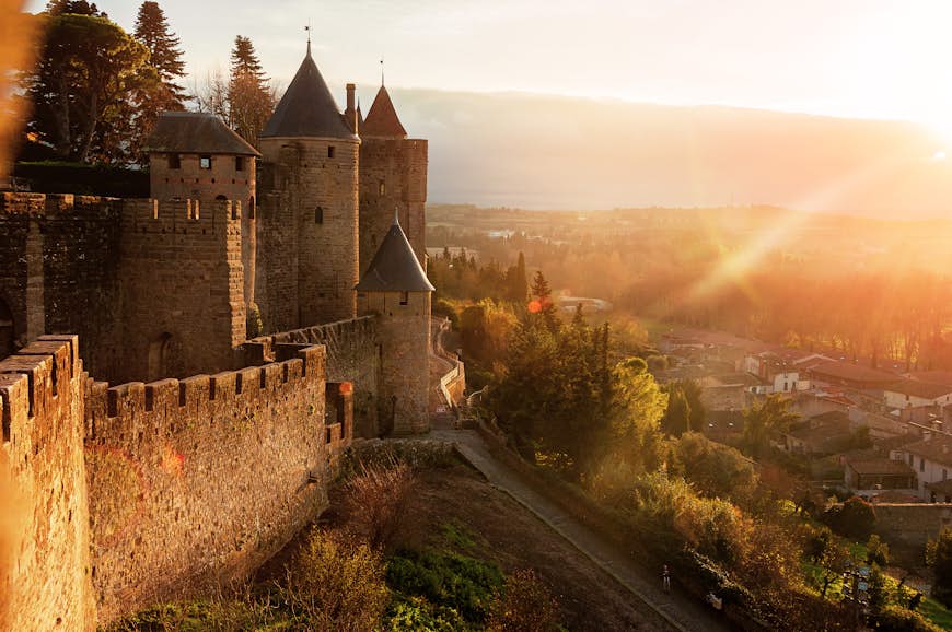 Ett medeltida slott lyser av den nedgående solen i Frankrike. 