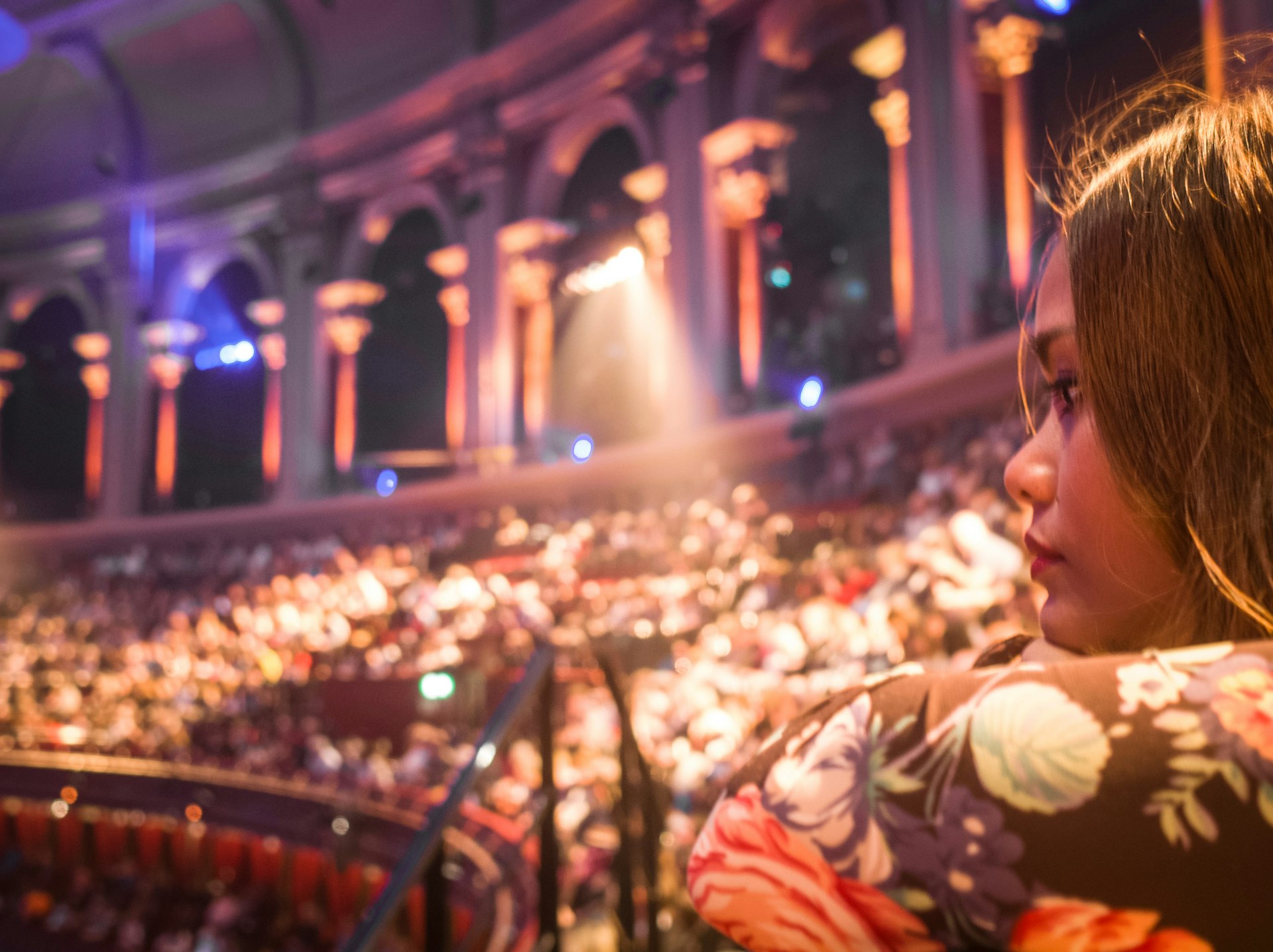 A woman watching a London West End show with blurred crowds of seated people in background