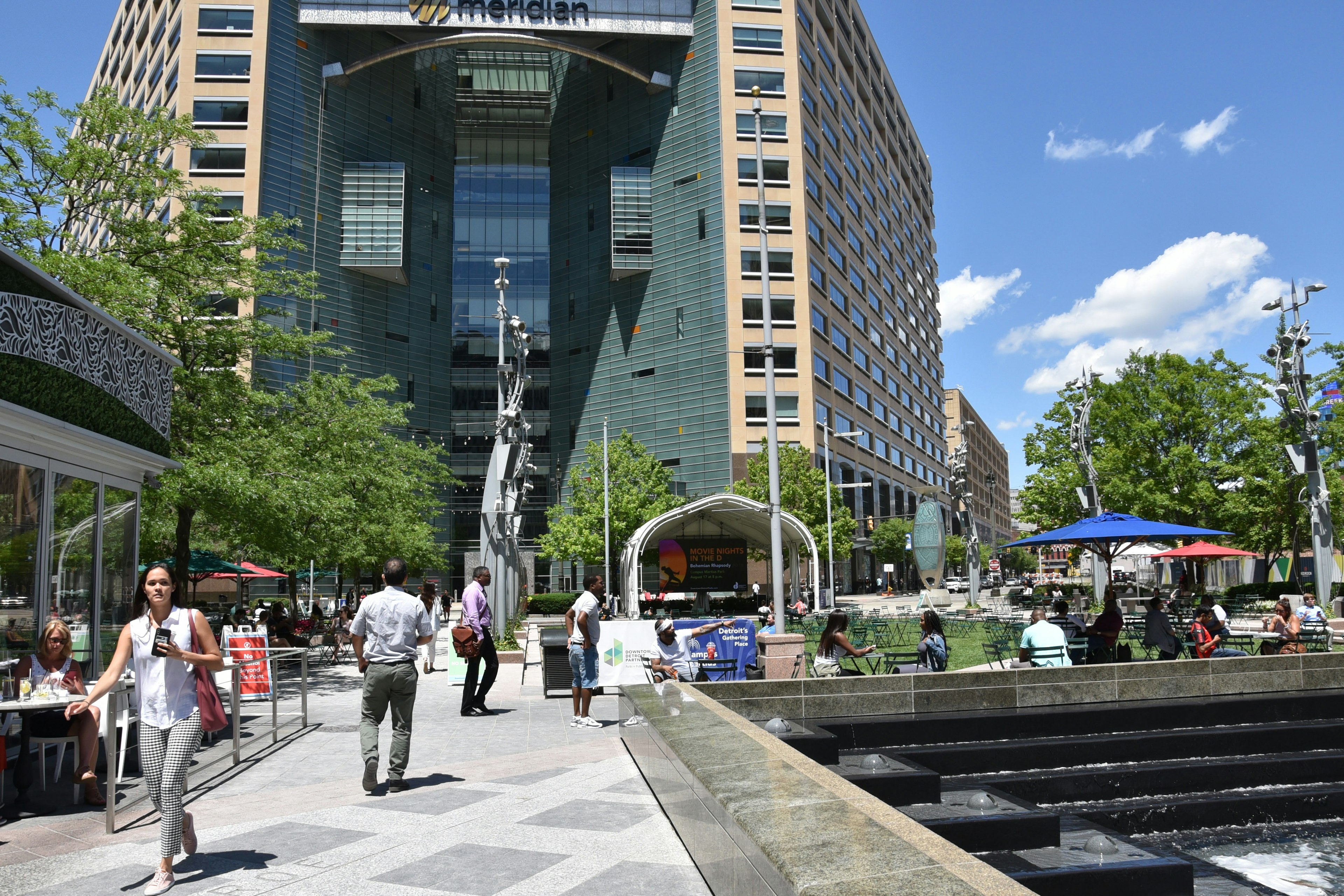 Pedestrians walking around Campus Martius park on a sunny day