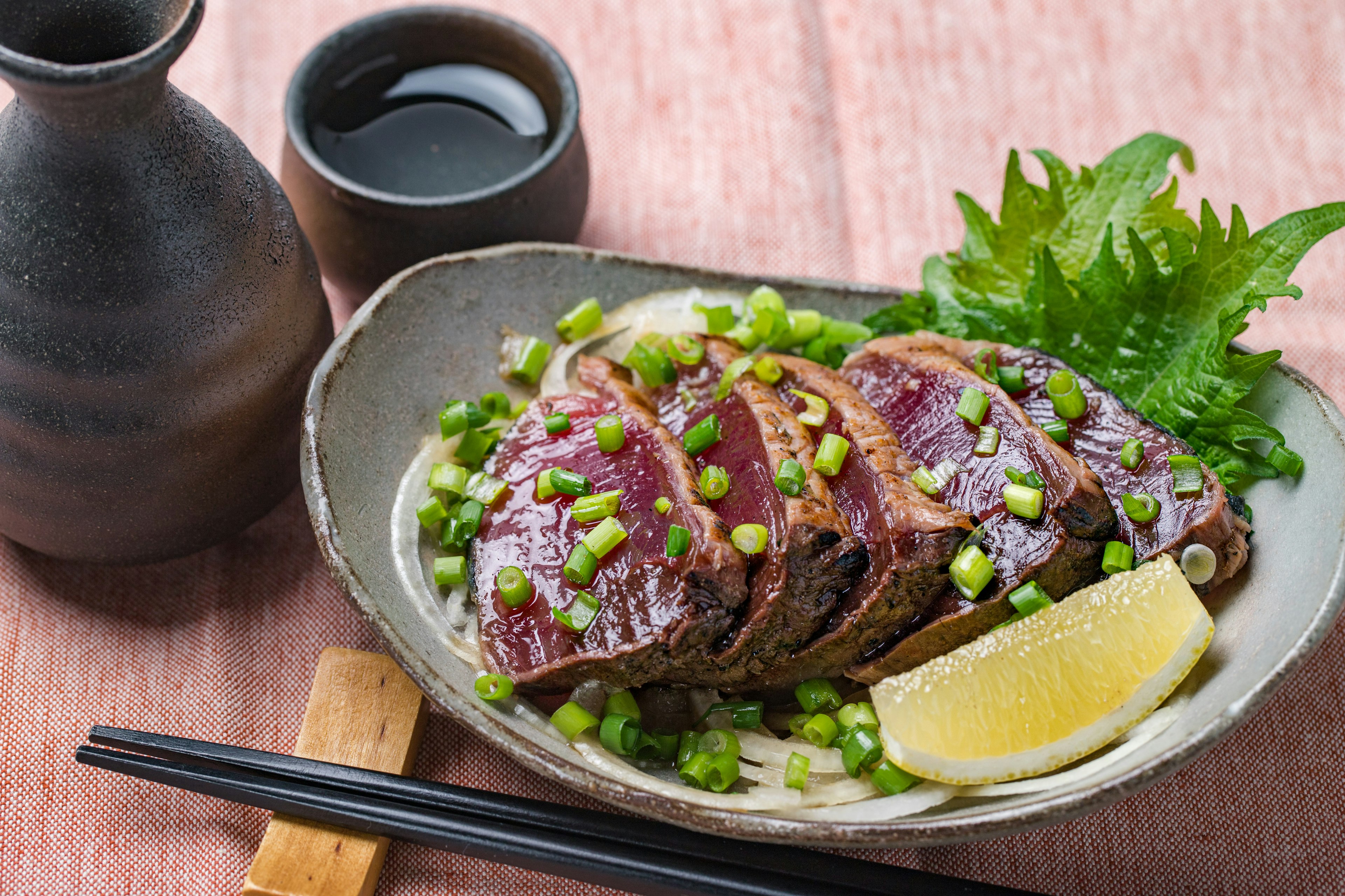 A bowl with seared slices of bonito, plus a bottle and glass of sake