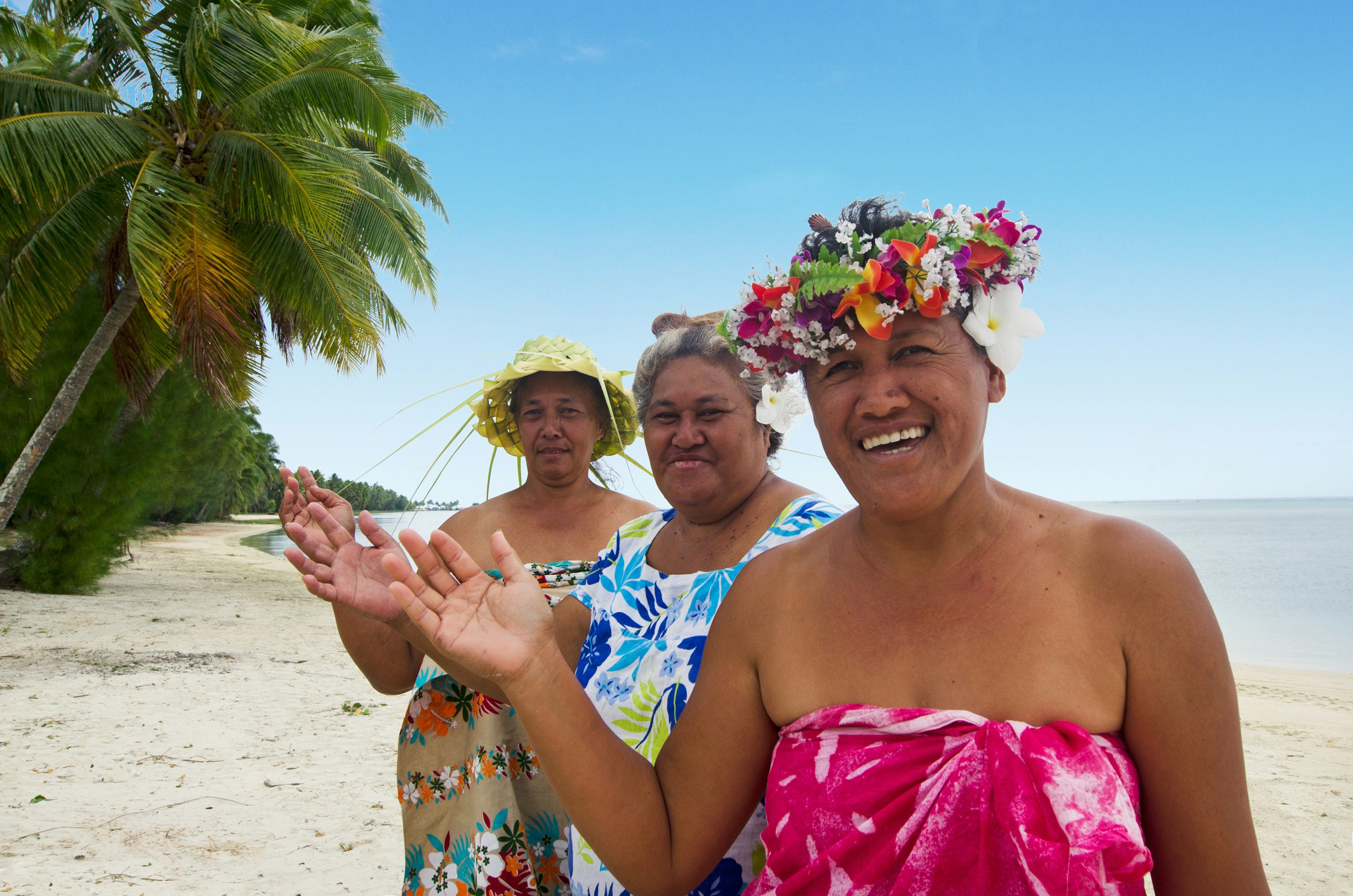 Friendly women wave on the beach of the Aitutaki Lagoon, Cook Islands