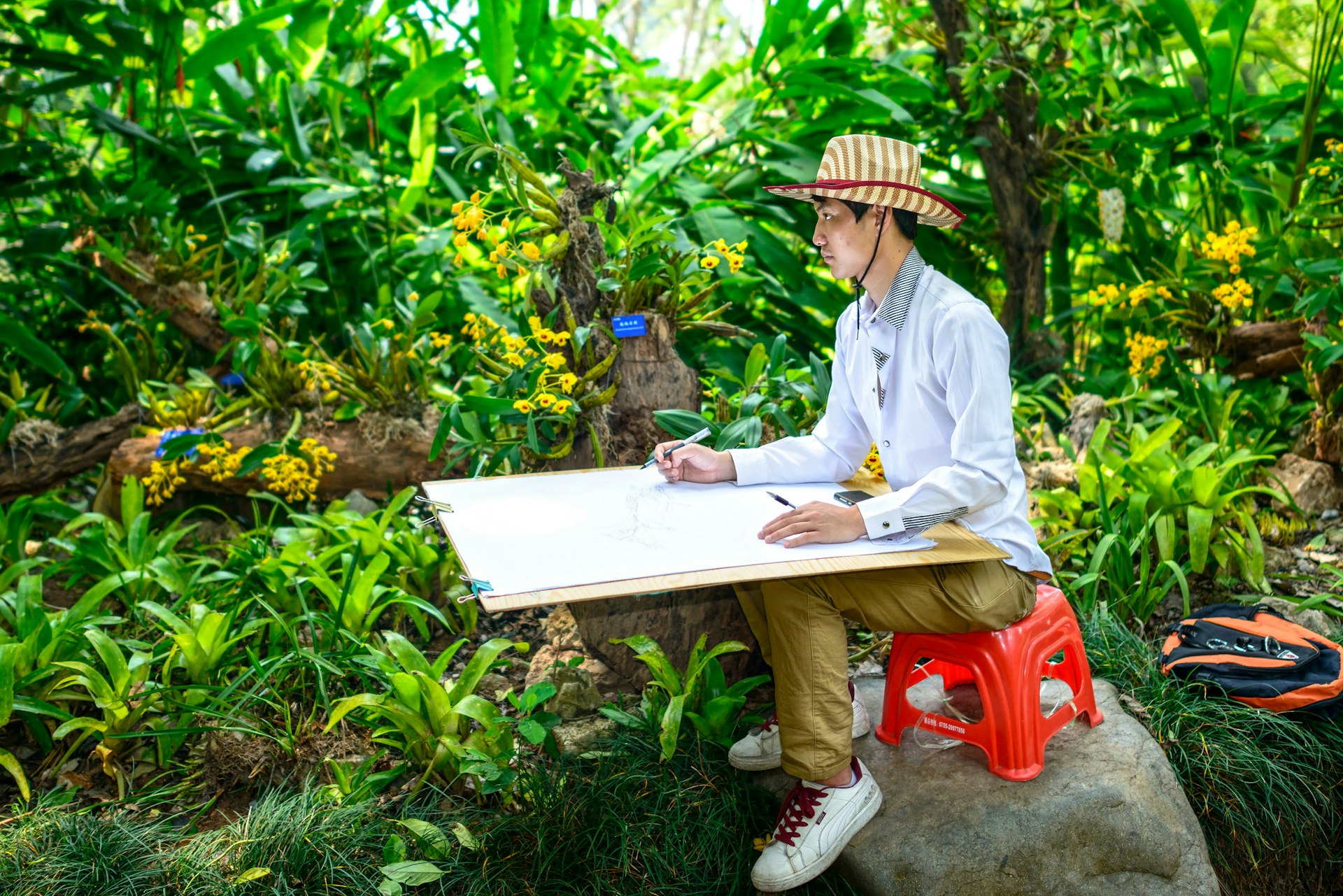 A young man painting sketch in Xishuangbanna Tropical Botanical Garden, Chinese Academy of Sciences. Located in Menglun Town, Mengla County, Yunnan Province, China.