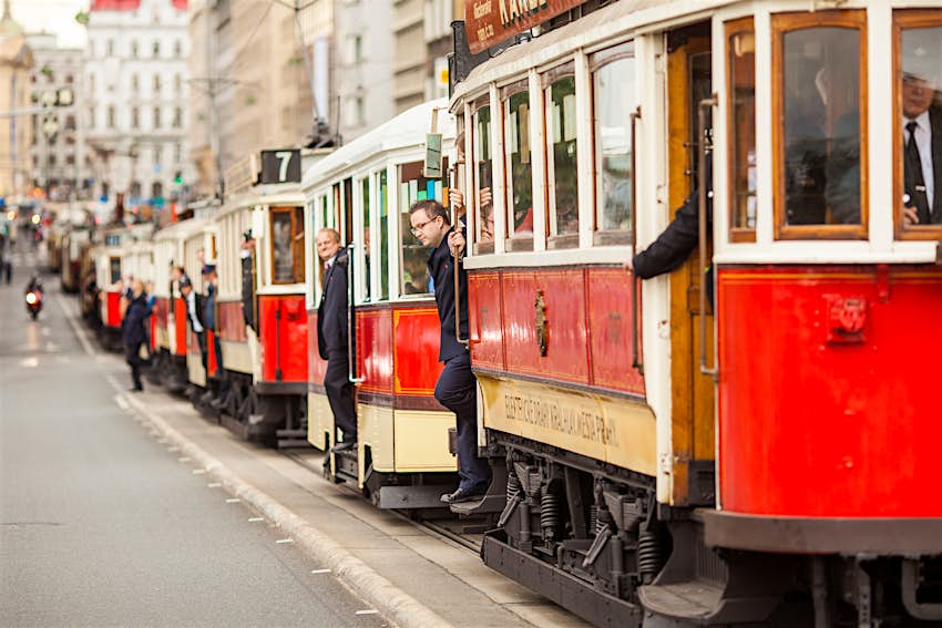 A parade of vintage red trams passes through the historic center of Prague