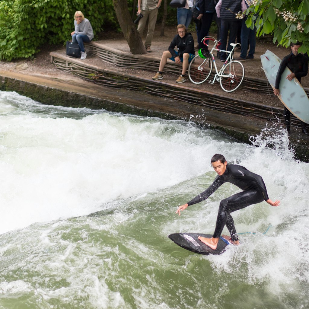 May  21, 2017: A man surfing on the Eisbach river in the English Garden, while others spectate.