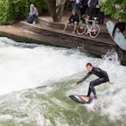 May  21, 2017: A man surfing on the Eisbach river in the English Garden, while others spectate.