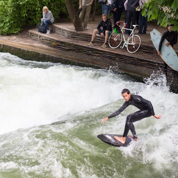 May 21, 2017: A man surfing on the Eisbach river in the English Garden, while others spectate.