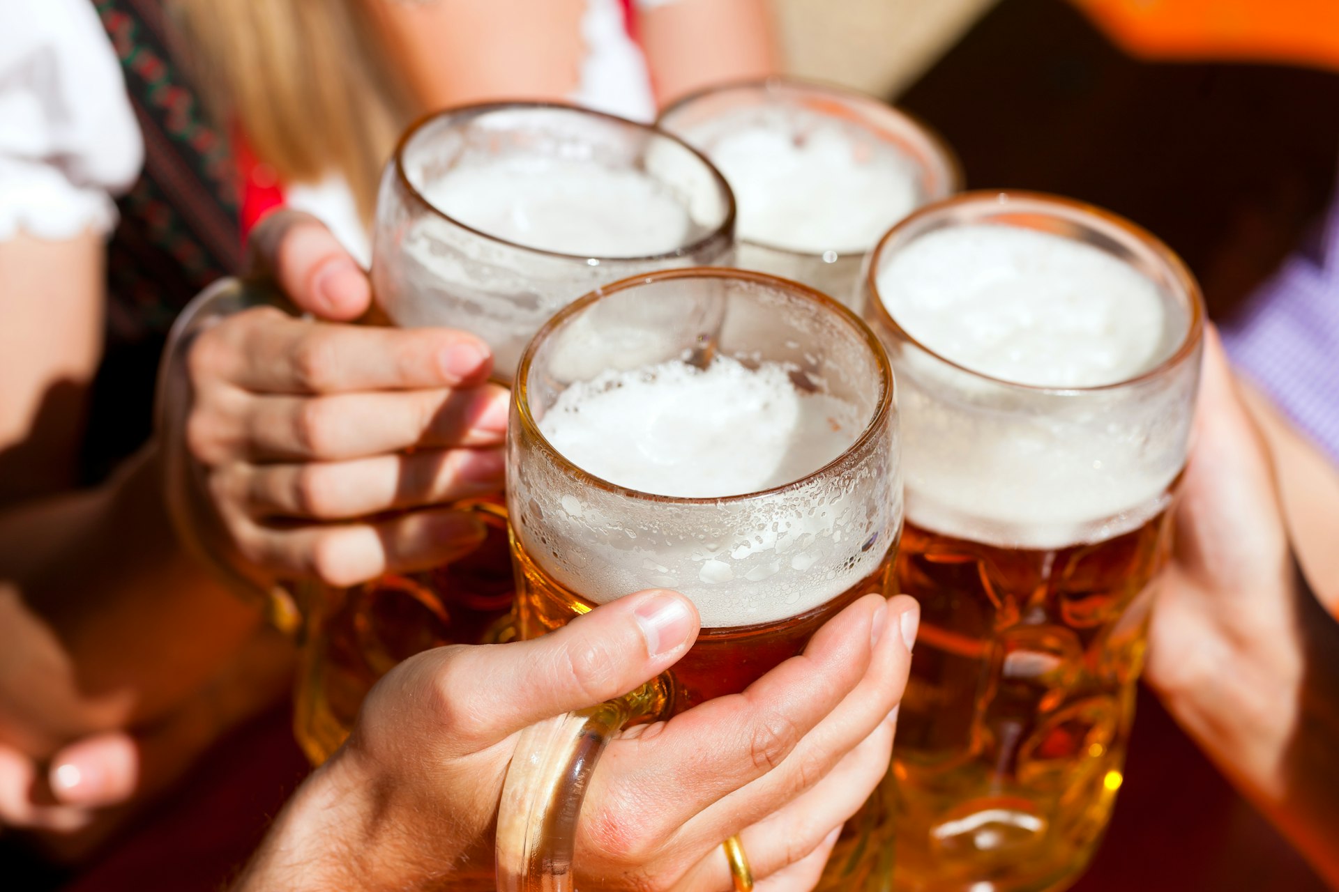 Four friends with toasting with beer steins in a beer garden