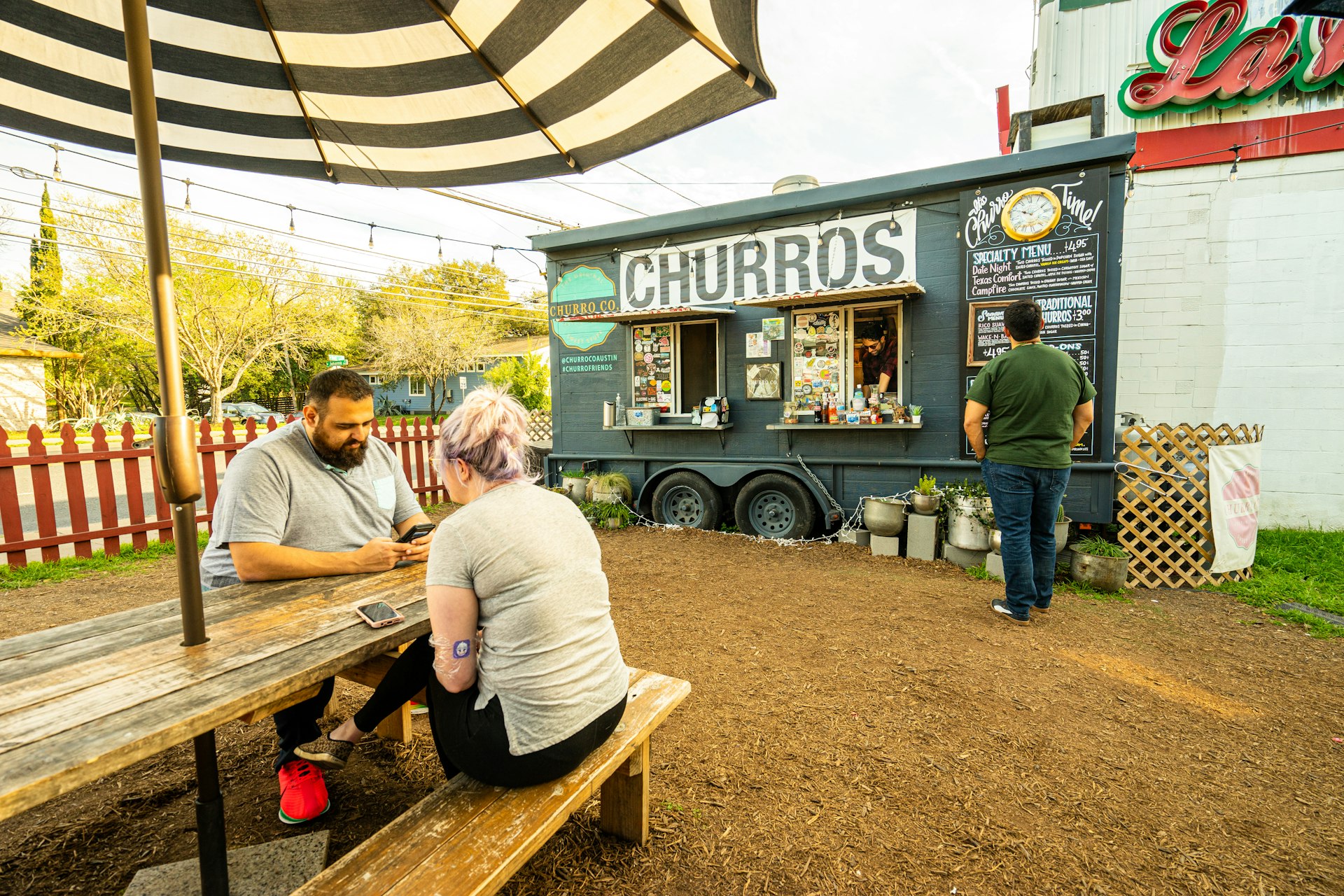 A man and woman sat at a bench eating at a local food truck in Austin, Texas