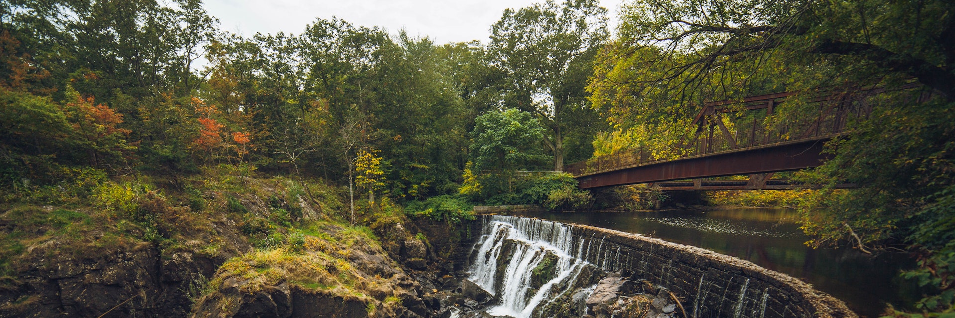 The thin streams of the waterfall are shot using the wide-angle lens, the skies are gloomy and the flora around is in dark warm colors, mostly green and yellow.