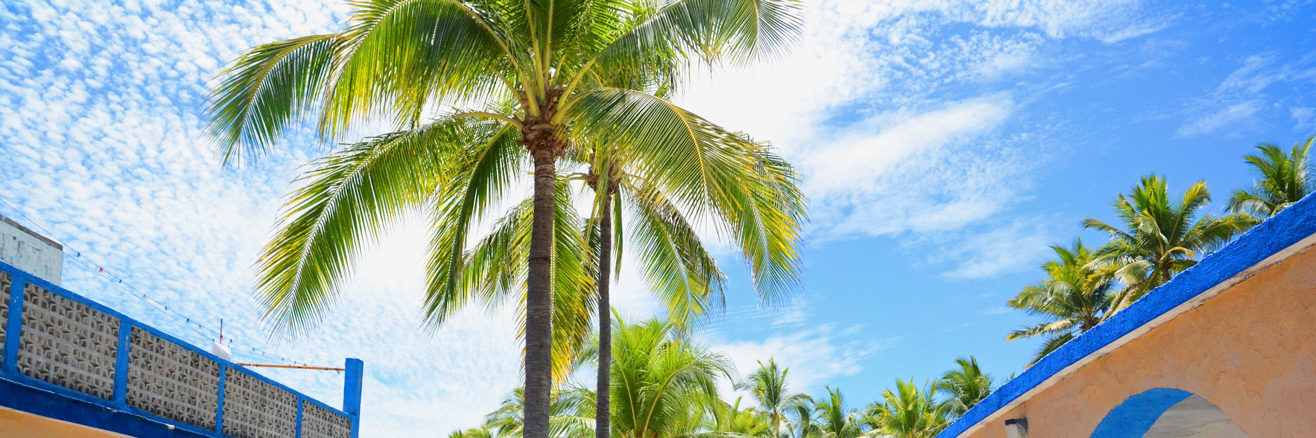 Melaque, Mexico. March 2015. Traditional Mexican single unit bungalows with palm trees and stone embedded  road.