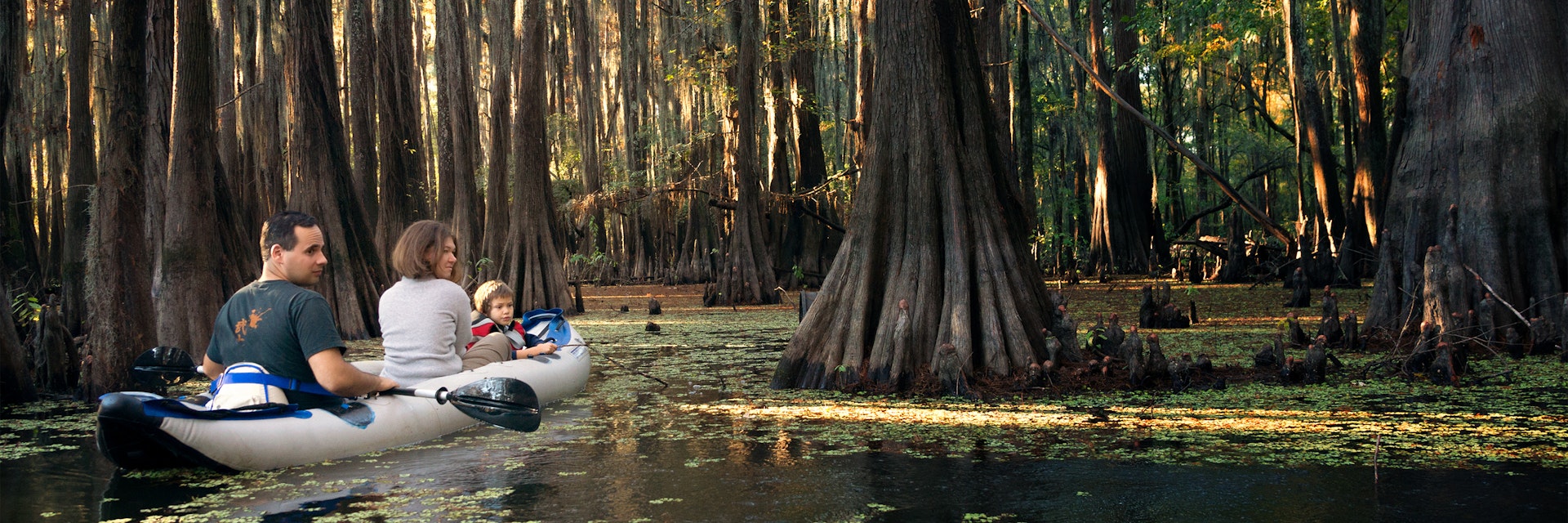 Family in an inflatable boat floats among the cypresses. Caddo Lake State Park, Texas, United States