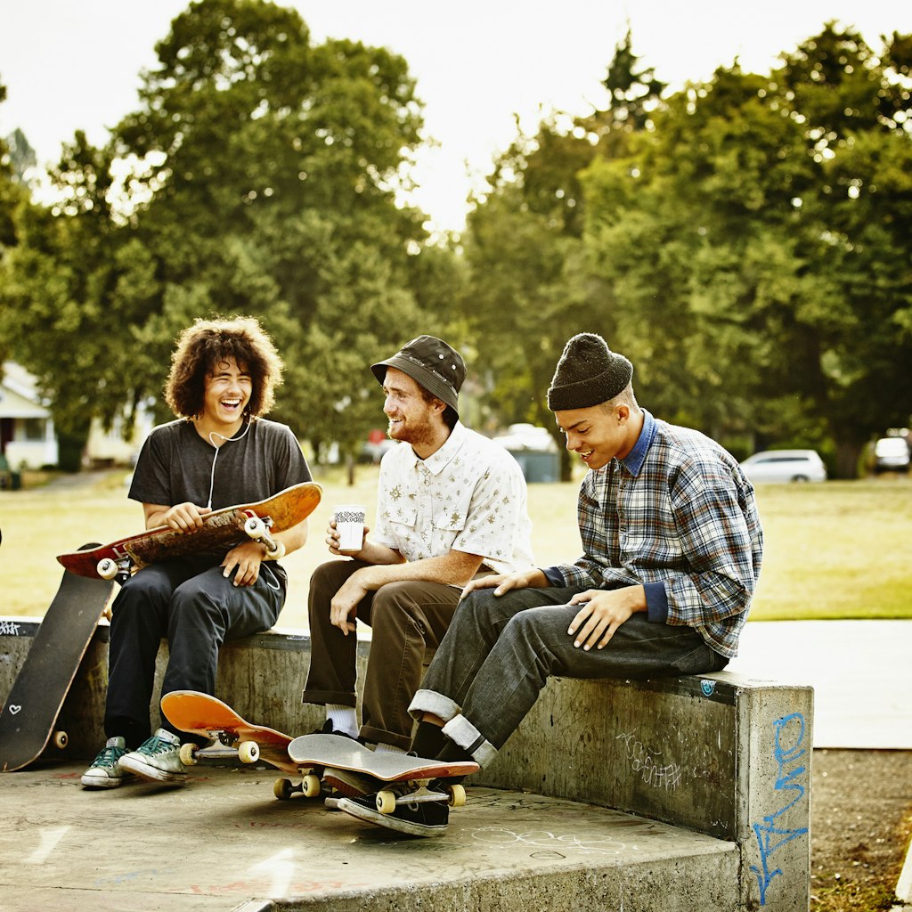 Group of laughing male and female skateboarders hanging out in neighborhood skate park in Seattle