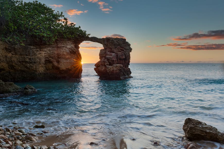 Titta på solnedgången genom den naturliga bron som bildas av stenar nära Cabo Rojo-fyren, Puerto Rico