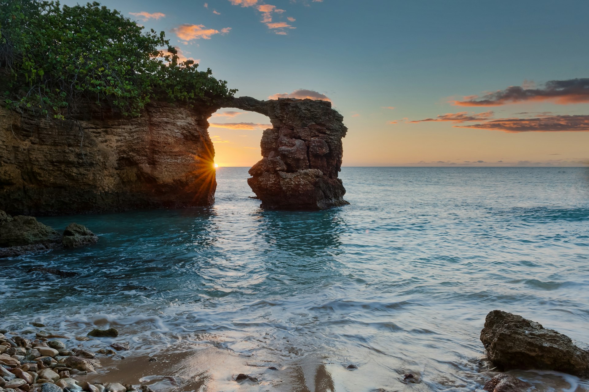 Looking at the sunset through the natural bridge formed by rocks near the Cabo Rojo Lighthouse, Puerto Rico