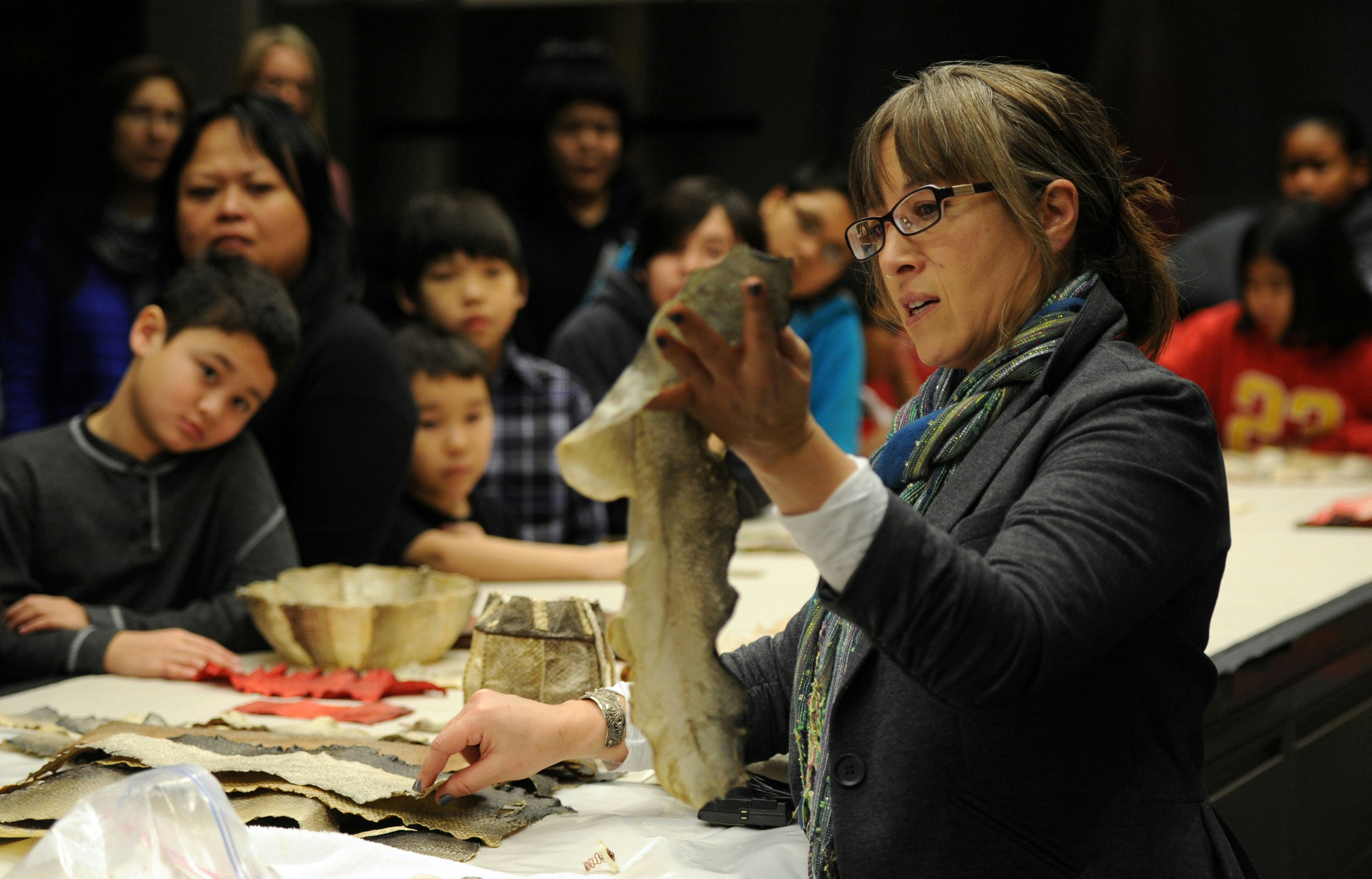 A woman holds a fish skin during a demonstration of Alaska Native practices