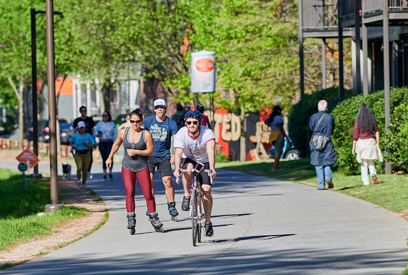 A group of people bike, roller blade and walk down the paved Atlanta Beltline.
