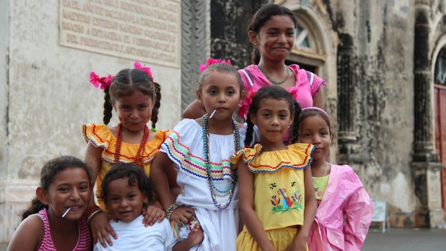 A group of girls in colorful outfits smiling in front a church in Granada, Nicaragua