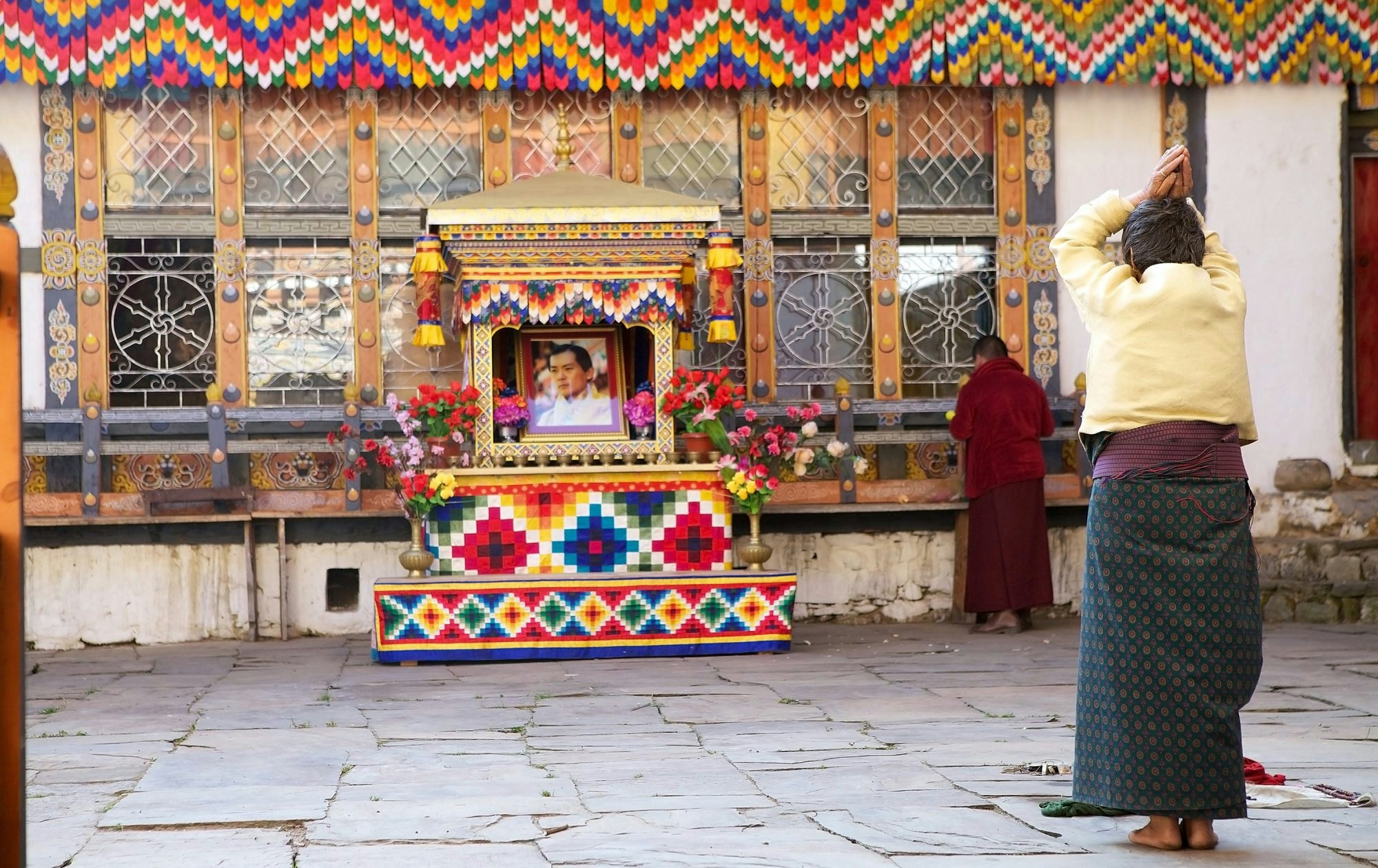 Chhoekhor, Bhutan - November 9, 2015: Pilgrim is praying at the Jampey Lhakhang temple, Chhoekhor, Bhutan with the image of the 5th King of Bhutan in the background. It is one of the oldest temple in Bhutan. It is said to date back to 7th century