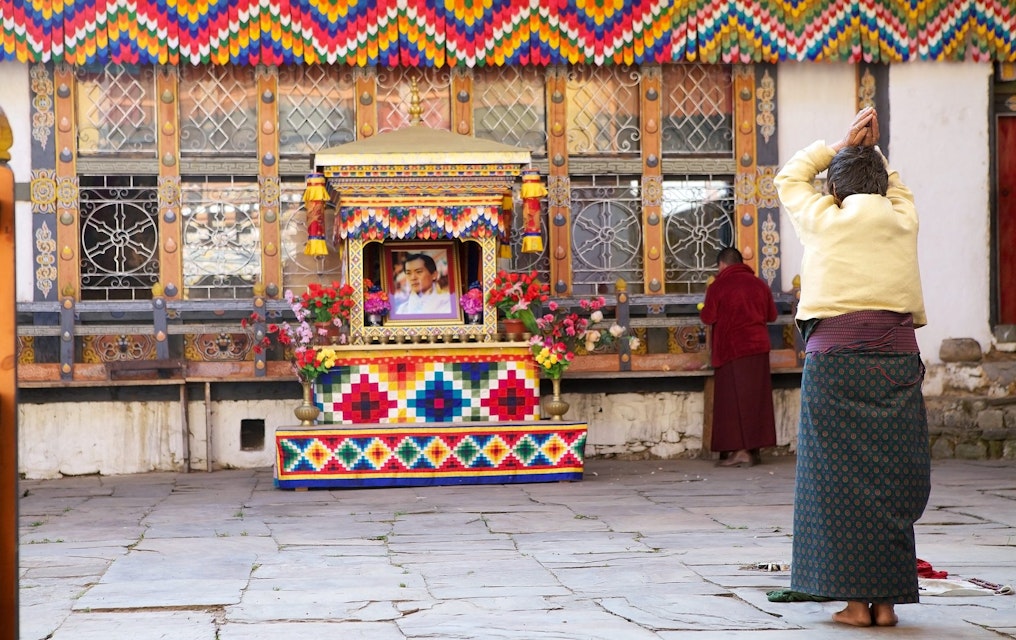 Chhoekhor, Bhutan - November 9, 2015: Pilgrim is praying at the Jampey Lhakhang temple, Chhoekhor, Bhutan with the image of the 5th King of Bhutan in the background. It is one of the oldest temple in Bhutan. It is said to date back to 7th century