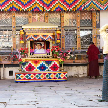 Chhoekhor, Bhutan - November 9, 2015: Pilgrim is praying at the Jampey Lhakhang temple, Chhoekhor, Bhutan with the image of the 5th King of Bhutan in the background. It is one of the oldest temple in Bhutan. It is said to date back to 7th century