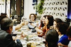 Multi-generational family toasting with wine glasses during dinner party in a restaurant in Mexico City