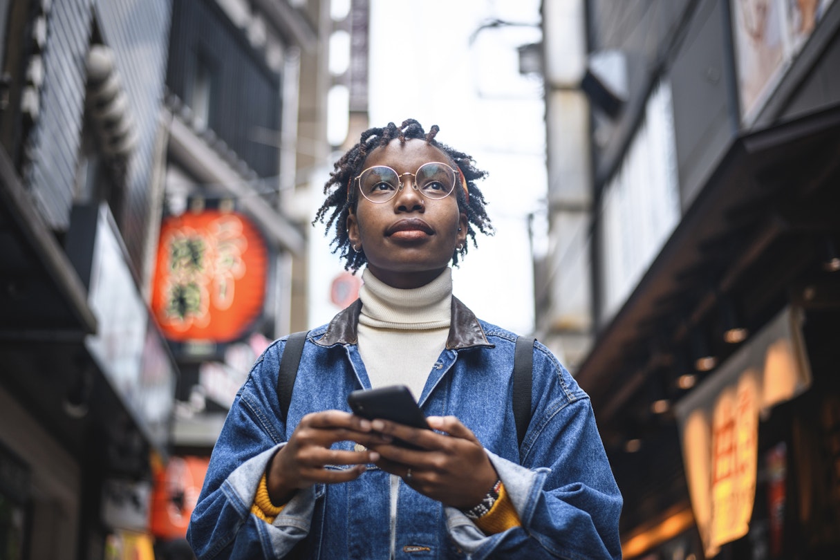 Young African female traveler attempting to find her way through the streets of urban Tokyo with a smartphone.