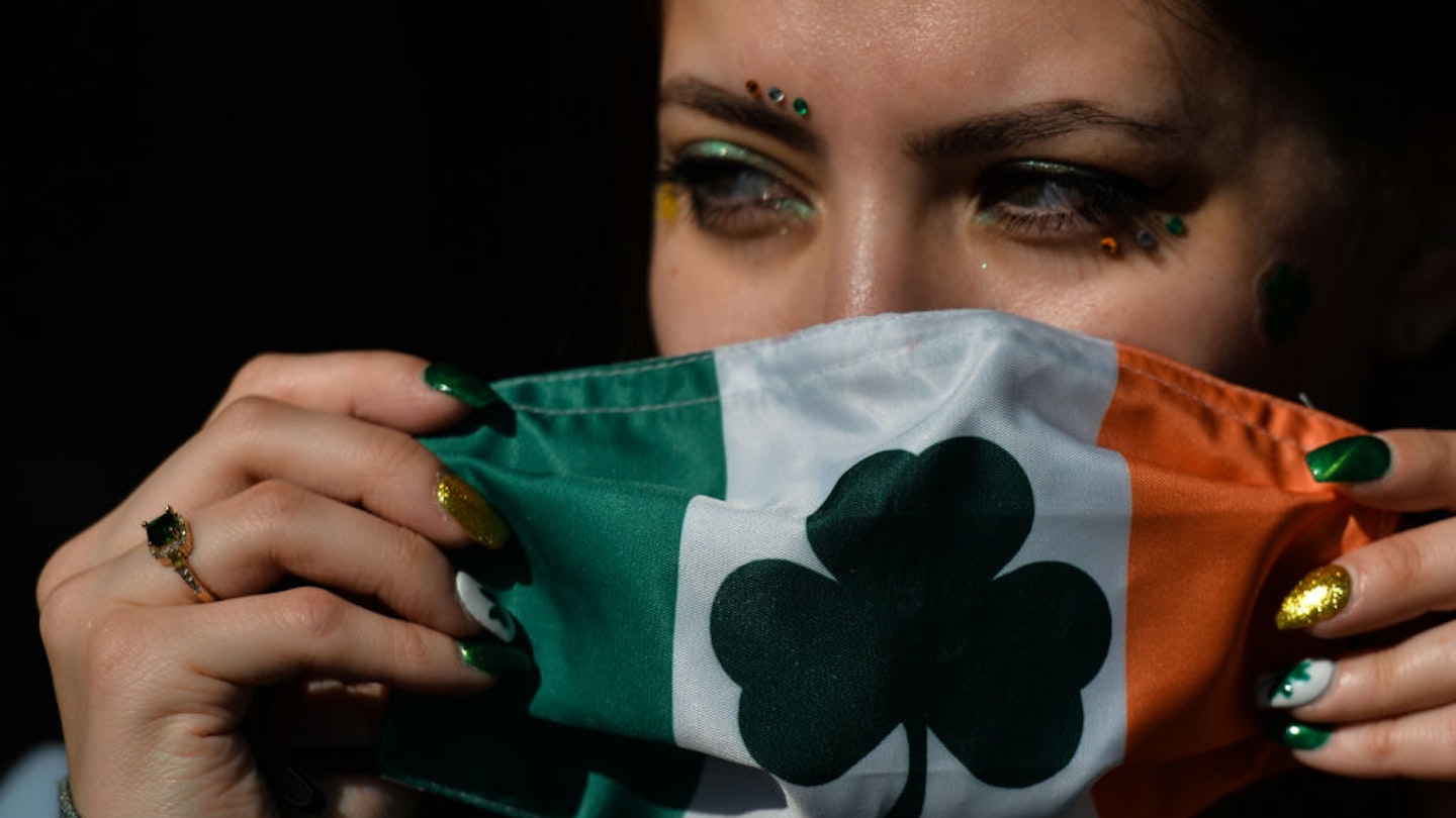 A young woman with fingernails decorated for St. Patrick's puts a face mask outside the Irish Potato Cake Company restaurant in Dublin's city center  on St. Patrick's Day. .On Wednesday, 17 March 2021, in Dublin, Ireland. (Photo by Artur Widak/NurPhoto via Getty Images)