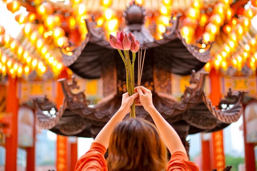 An Asian woman offering fresh lotus flower and incense sticks at Thean Hou Temple, Kuala Lumpur