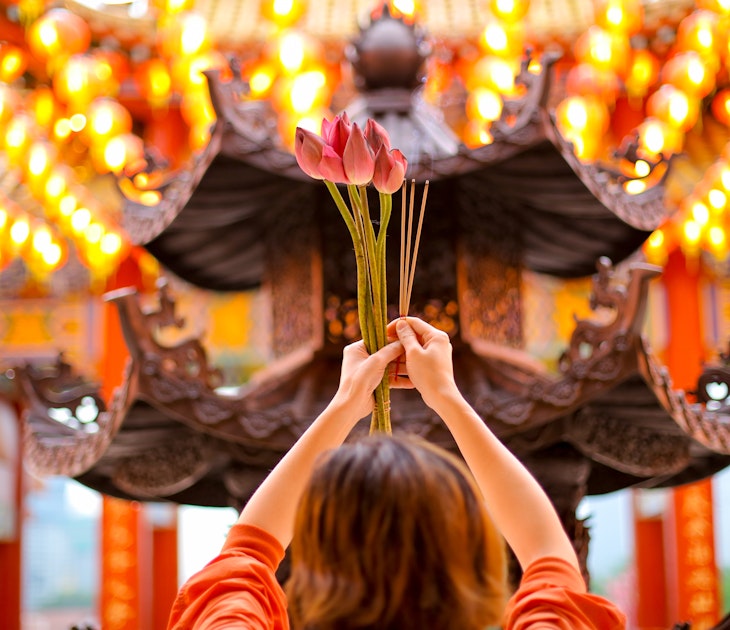 An Asian woman offering fresh lotus flower and incense sticks at Thean Hou Temple, Kuala Lumpur