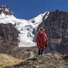 A hiker in a poncho in front of Condoriri Peak in the Bolivian Andes