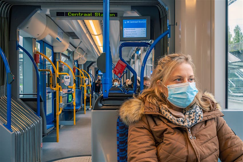 Una mujer con mascarilla en el transporte público  
