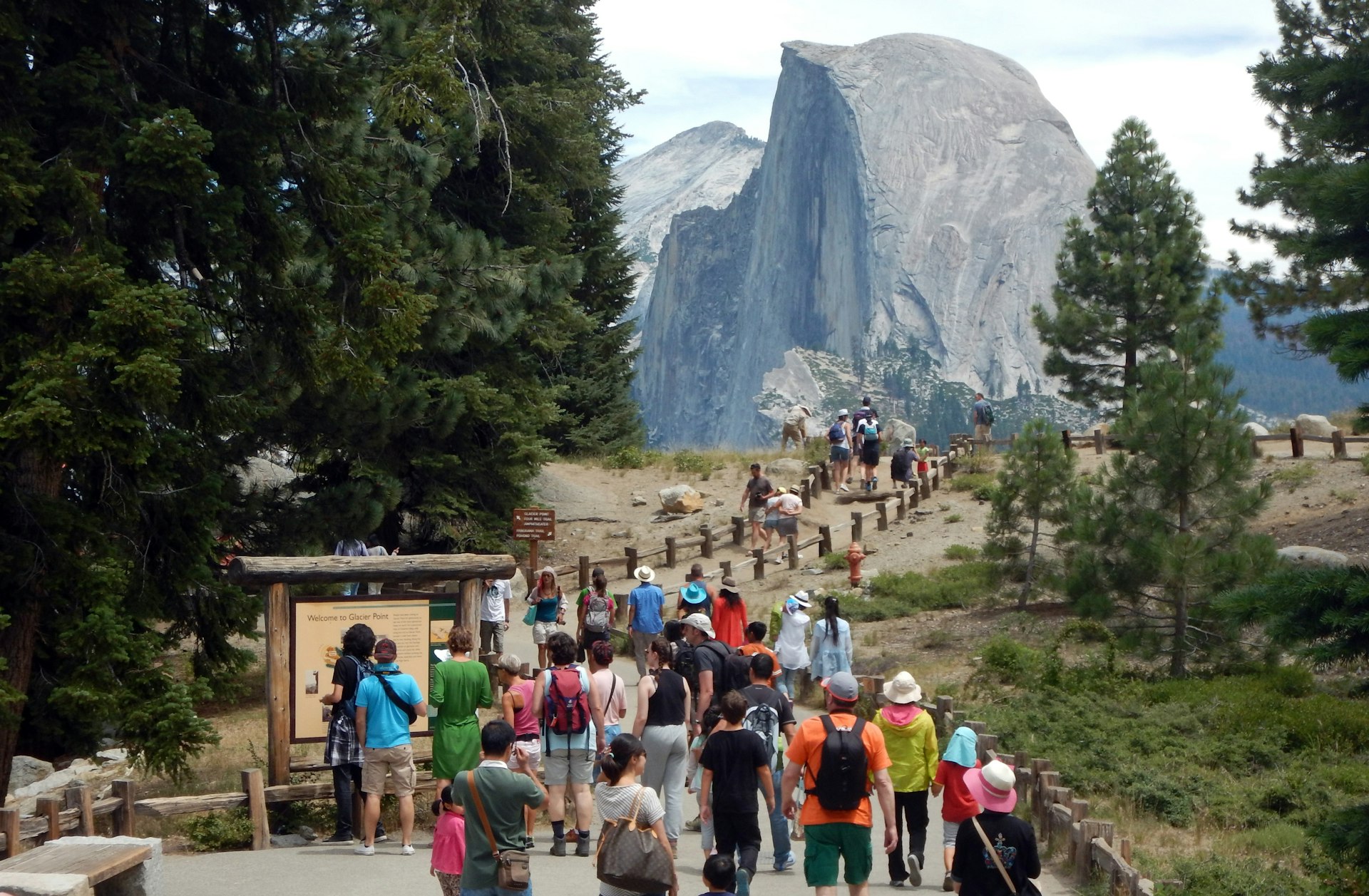 A crowd of tourists walking to Glacier Point with a background view of Half Dome at Yosemite National Park.