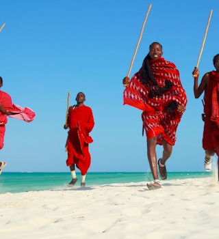 Four Maasai warriors running on the beach in Tanzania