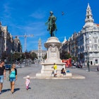 Young family passing by the King Dom Pedro IV statue on Avenida dos Aliados in Porto, Portugal