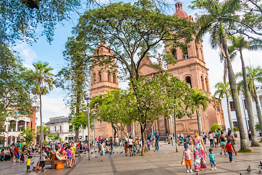 A plaza filled with people in Santa Cruz de la Sierra in Bolivia with the Basilica de San Lorenzo in the background