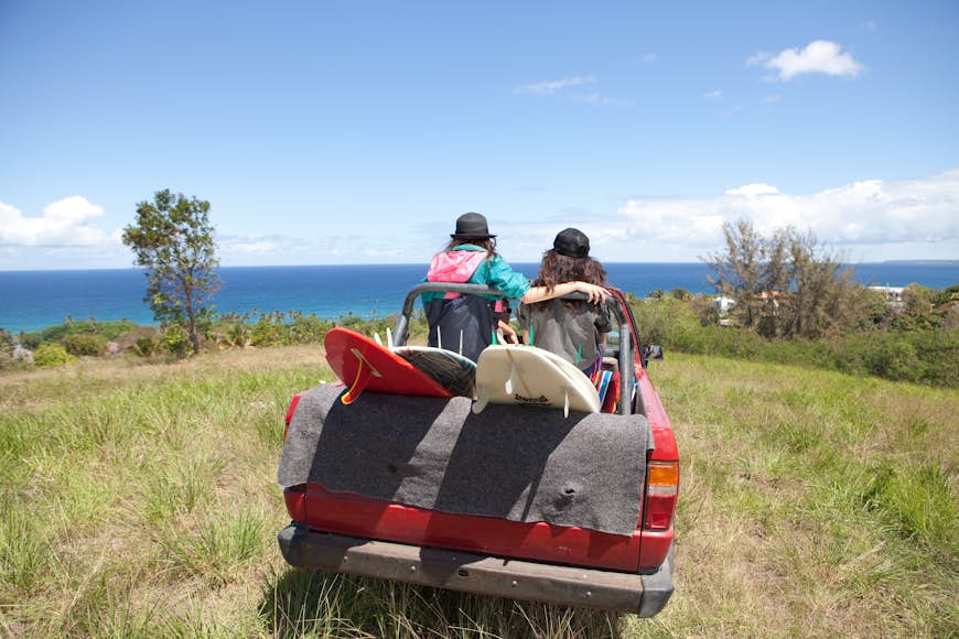 Terrängfordon som kör mot stranden med två kvinnor i ryggen