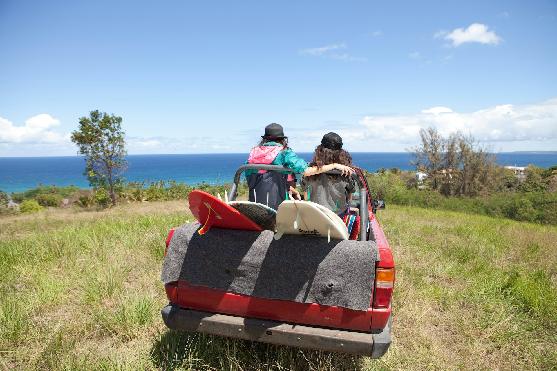 Veículo off-road dirigindo em direção a uma praia com duas mulheres atrás