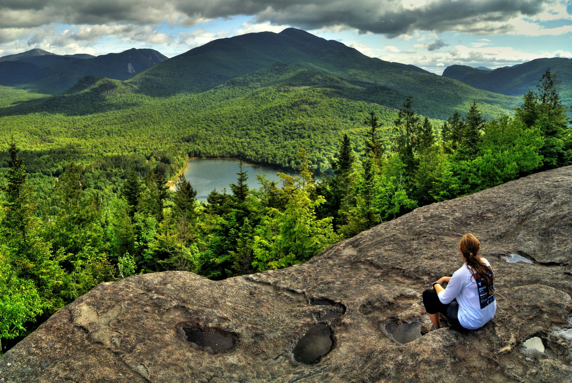 Female hiker takes in the view of the Adirondack High Peaks and Hear Lake