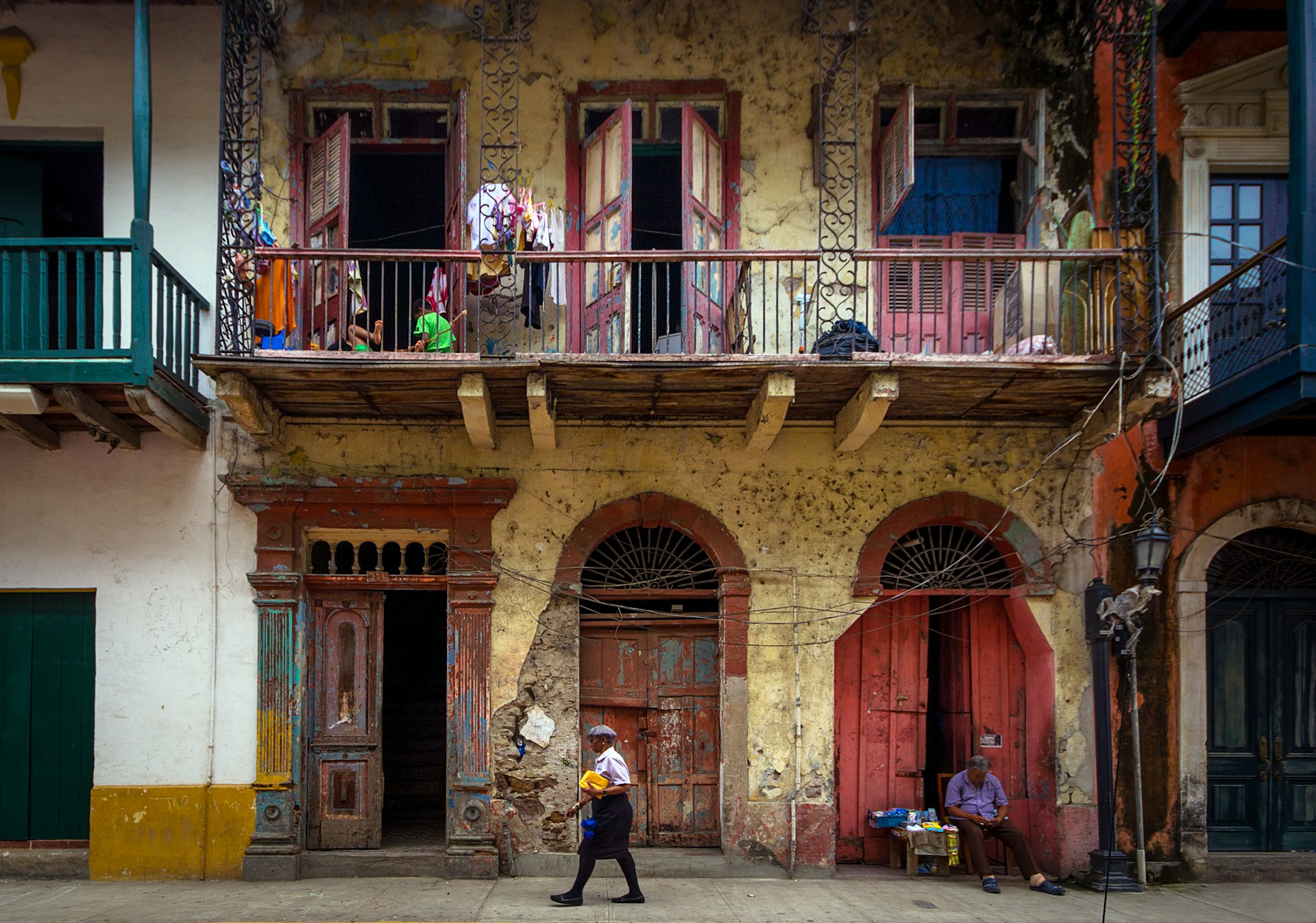 Woman walking the streets and a vendor sleeping, in historic Casco Viejo district of Panama City, Panama. 