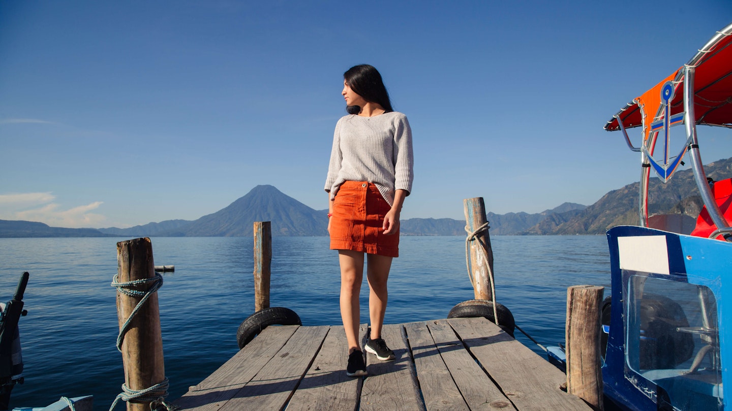 Hispanic woman on the pier of Lake Atitlan in Guatemala looking aside, full body