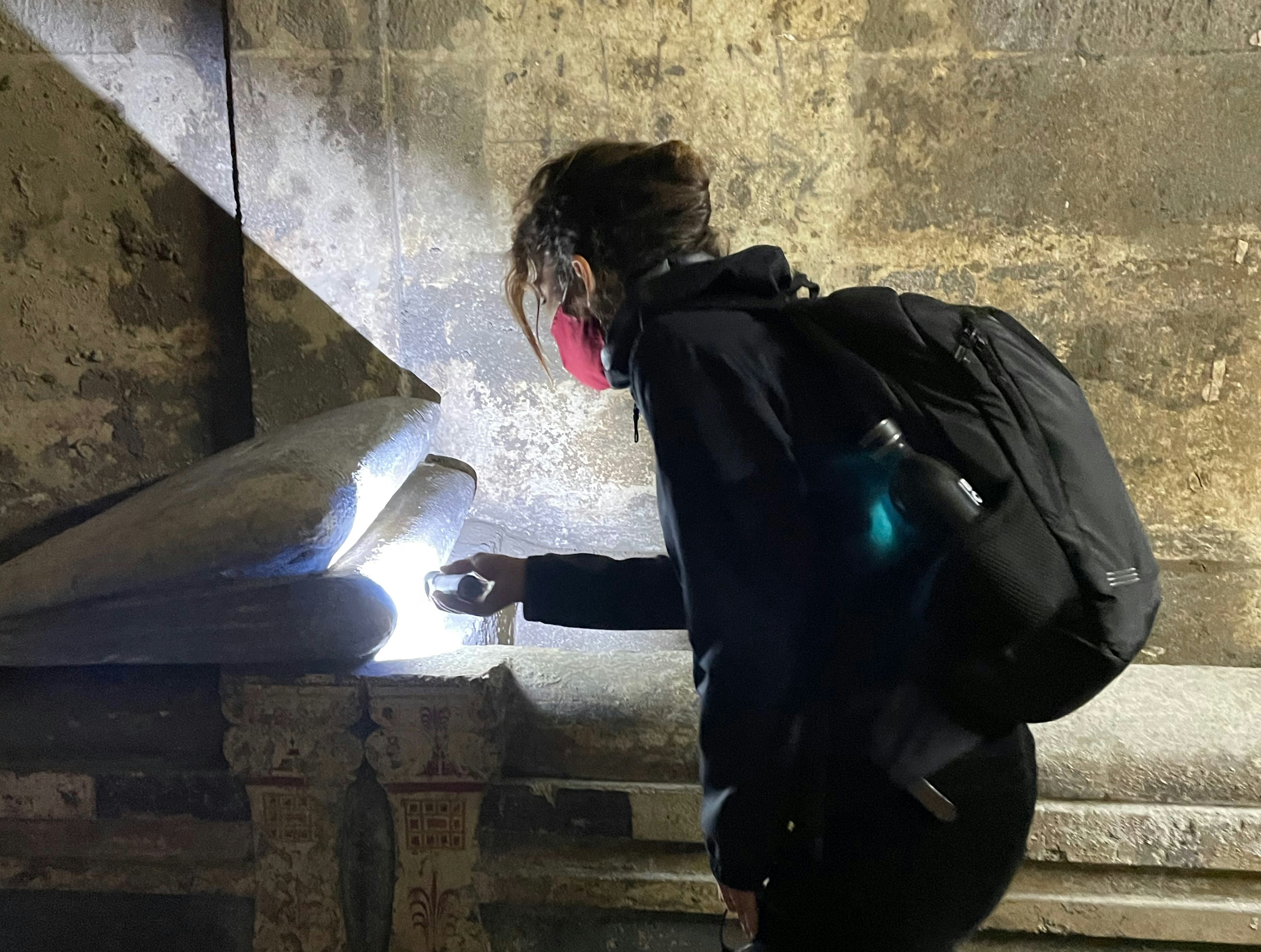 An archaeologist examines one of the burial beds with a torch