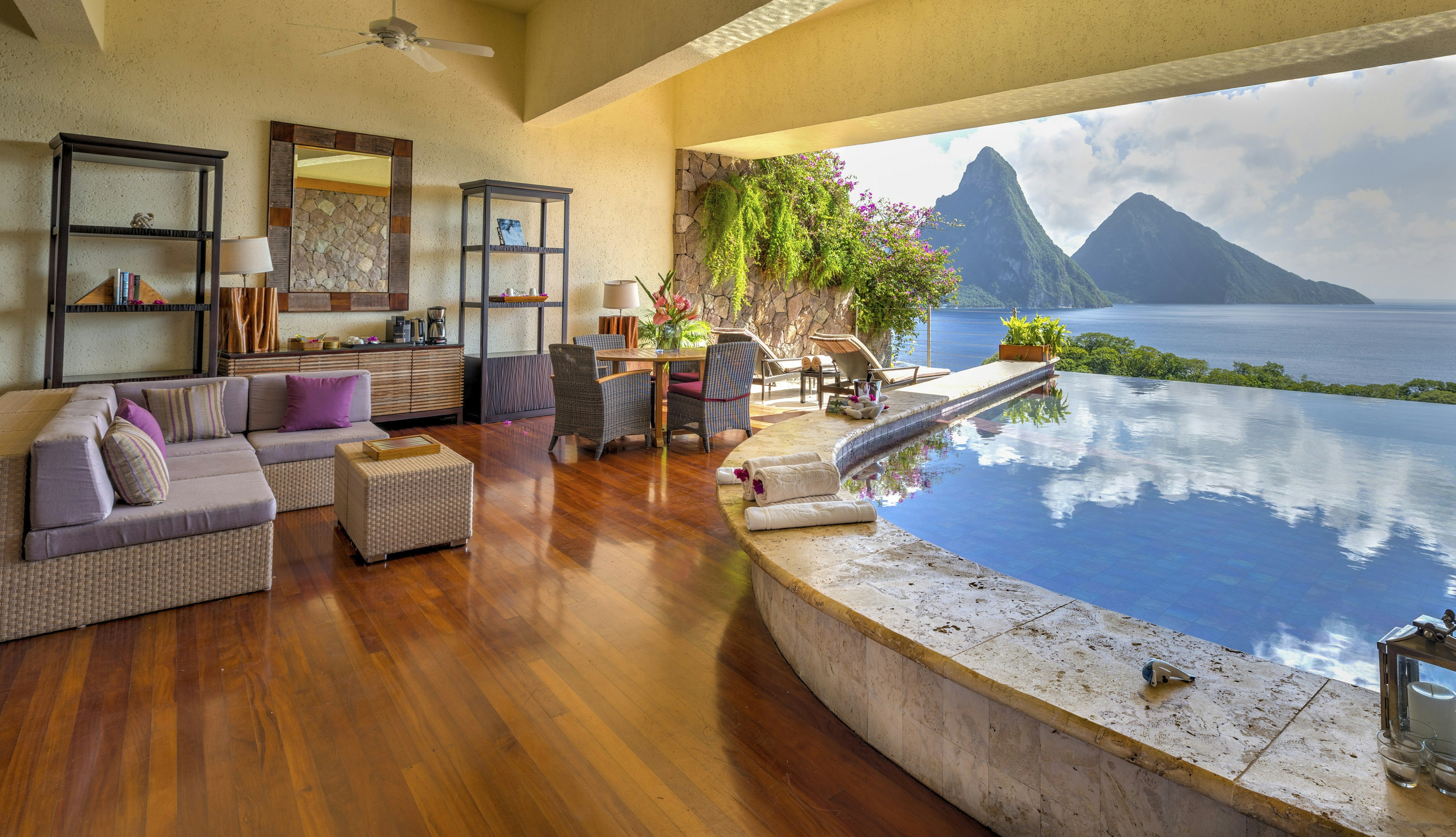 A hotel room with an infinity pool stretching out towards a mountain peak by the sea