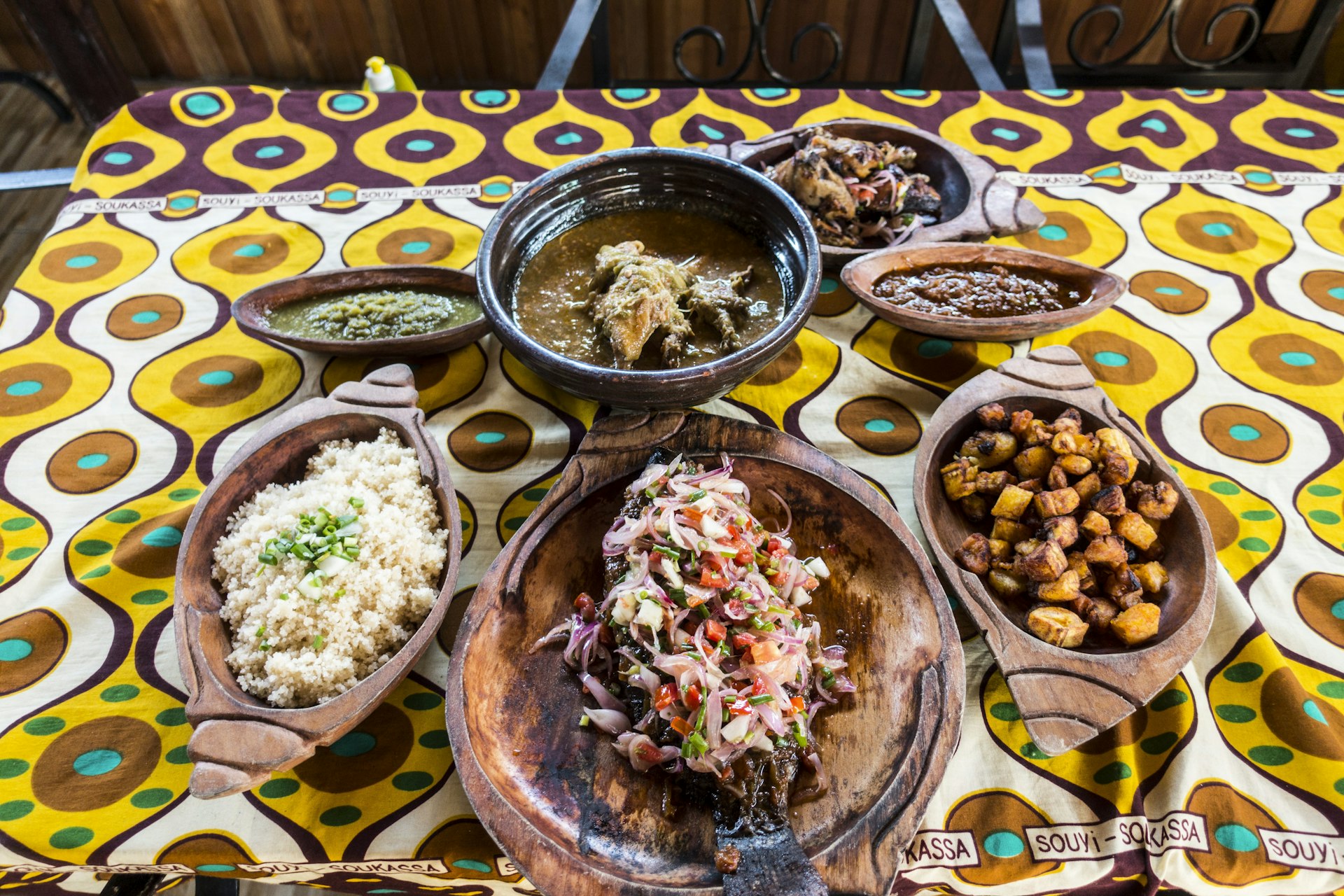 Separate Ghanaian dishes laid out on a yellow-and-brown table cloth