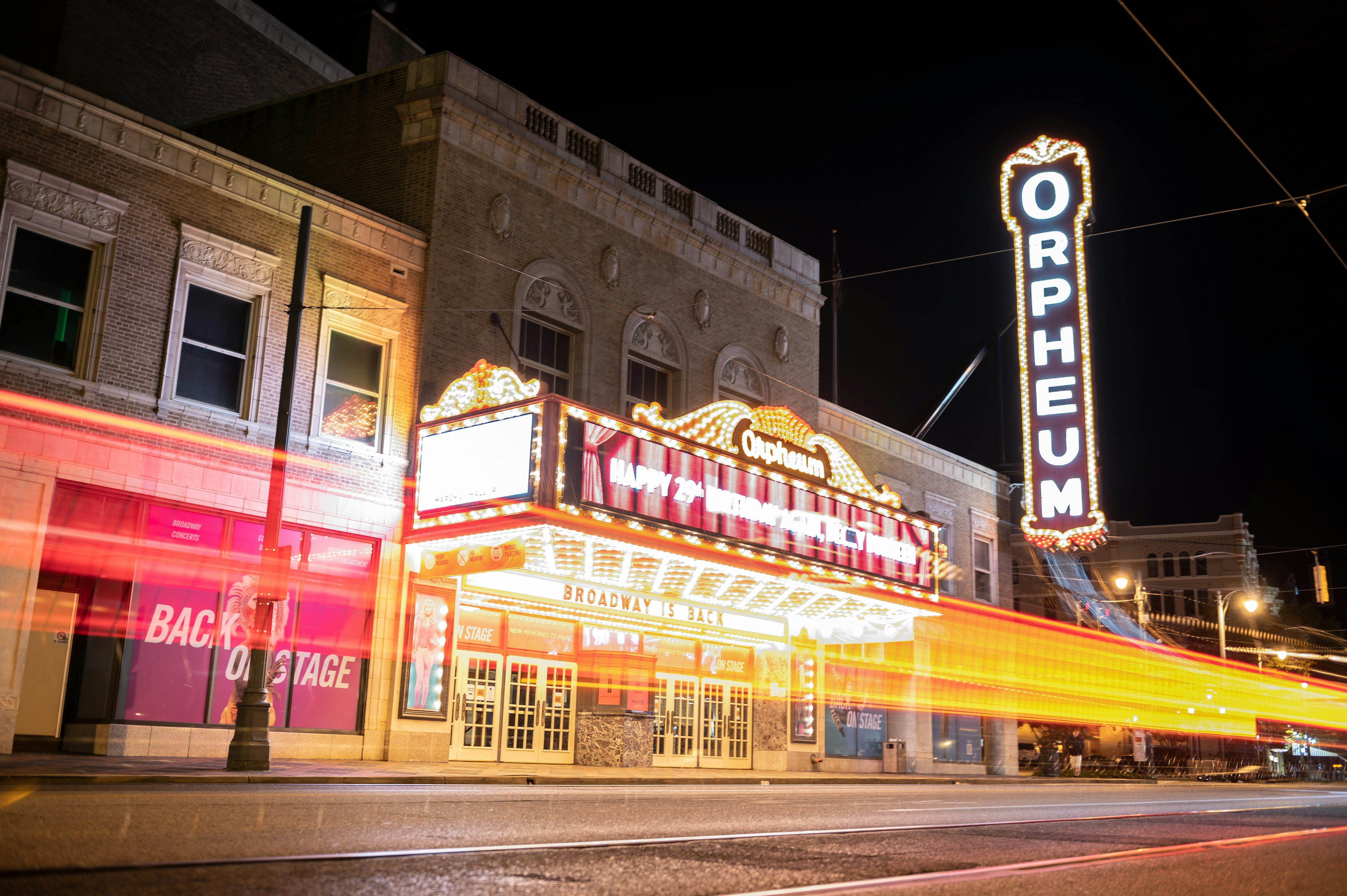 The neon frontage of a theater, with a large lit-up vertical sign that says