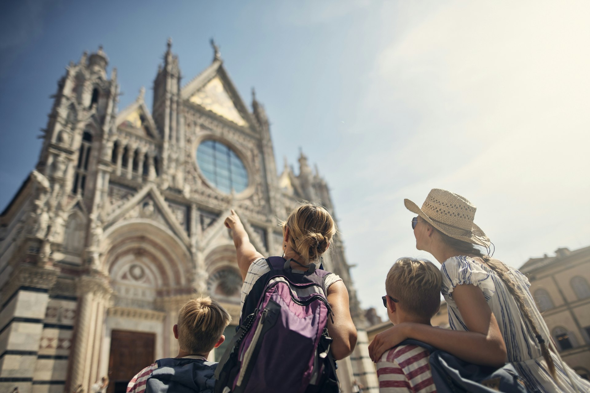 Mãe e filhos passeando pela cidade de Siena, Toscana, Itália, com a mãe apontando para a Catedral