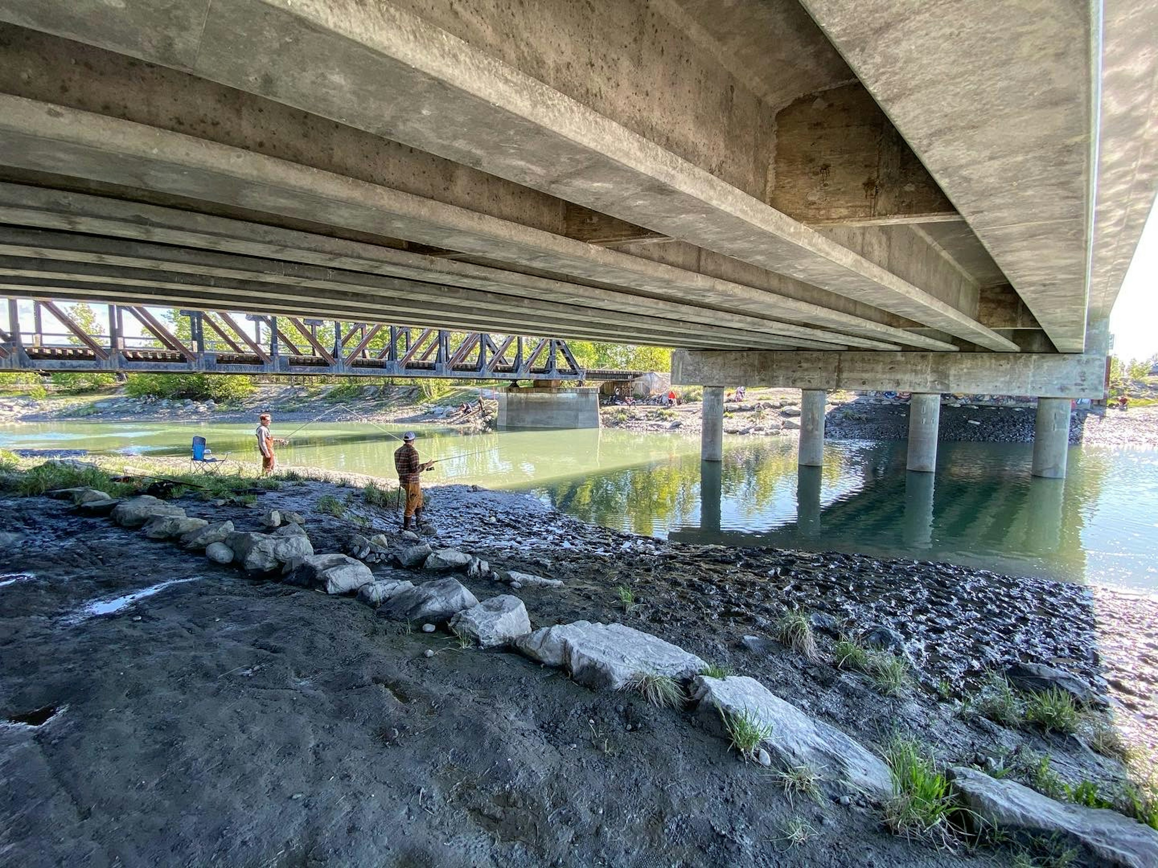 Fishers casting under a large concrete bridge