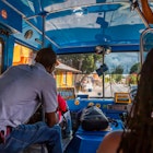 Shot from inside of a Reggae Reggae bus looking through the windshield. There are people sitting around the bus.