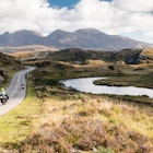 The A837 road, part of the North Coast 500 route, meanders past rivers and low hills in the glacial landscape of Assynt, with Quinag mountain in the distance, in the Northwest Highlands of Scotland.; Shutterstock ID 1114531469; your: Claire naylor; gl: 65050; netsuite: Online ed; full: Great British road trips update