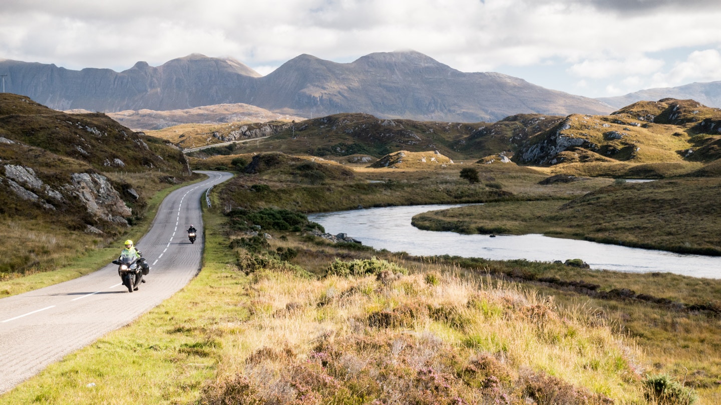 The A837 road, part of the North Coast 500 route, meanders past rivers and low hills in the glacial landscape of Assynt, with Quinag mountain in the distance, in the Northwest Highlands of Scotland.; Shutterstock ID 1114531469; your: Claire naylor; gl: 65050; netsuite: Online ed; full: Great British road trips update